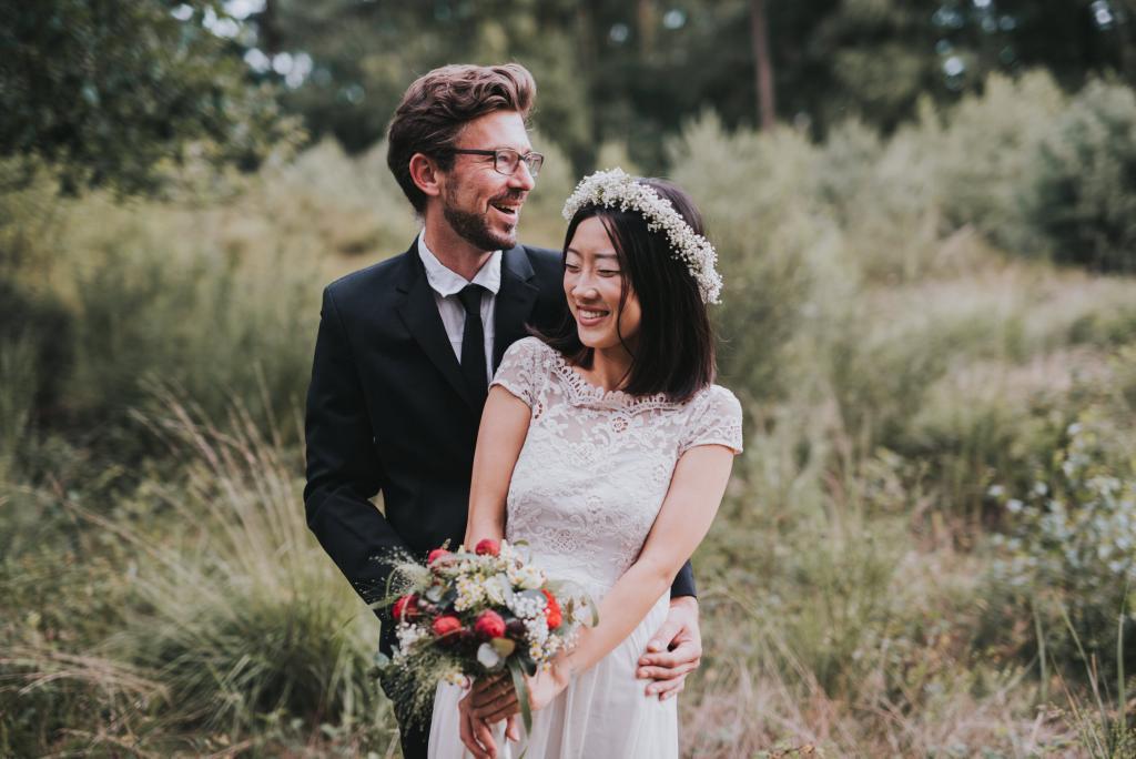 Kuschelndes Brautpaar mit Brautstrauß